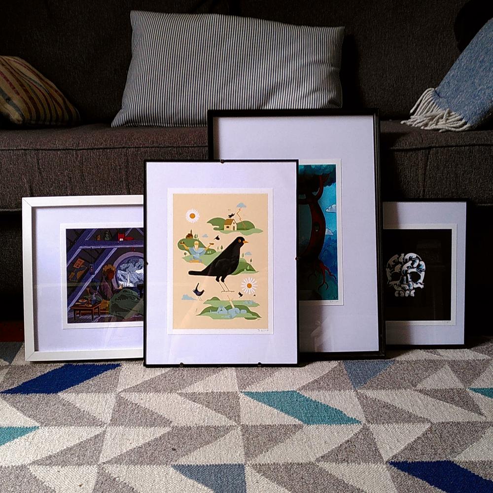 Some of my new prints in various frames in front of a sofa. Front and centre is a piece featuring a cute blackbird, they're the best.